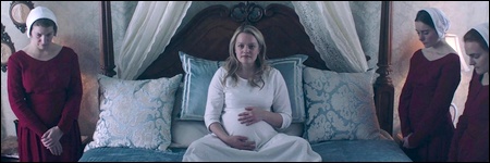 June, enceinte, trône dans son lit au milieu des Servantes